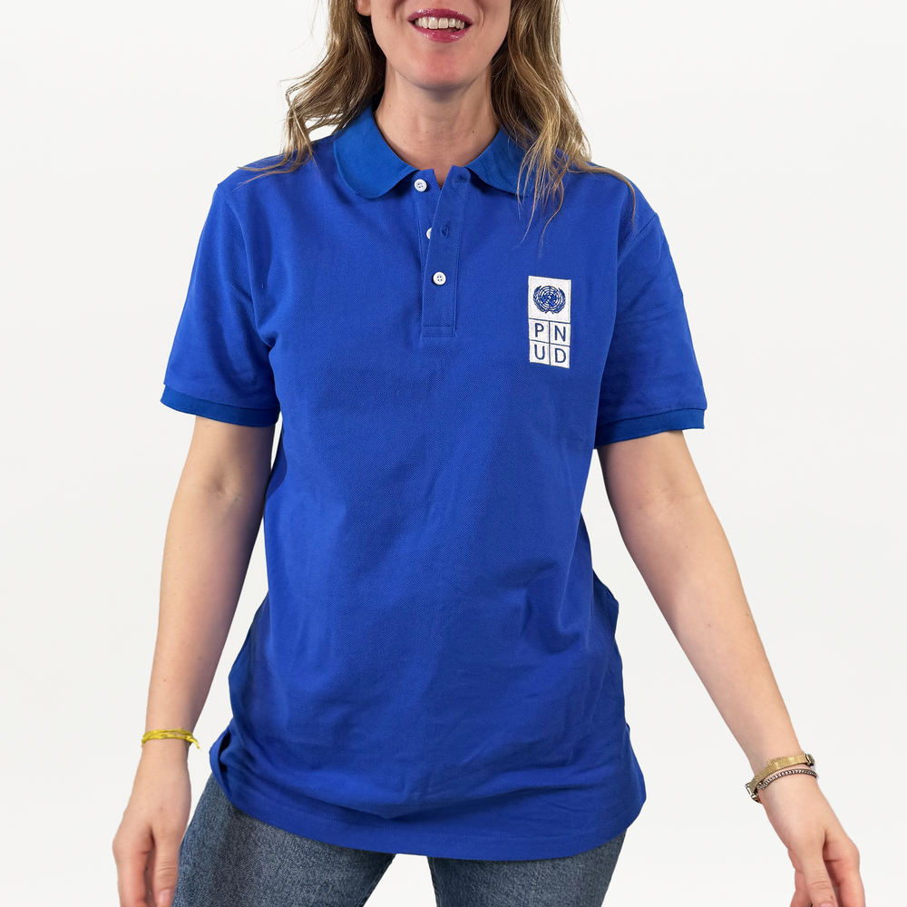 A woman wearing a blue polo shirt with a white and blue PNUD logo on the right.