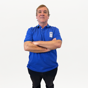 A man with crossed arms, wearing a blue polo shirt with a white and blue UNDP logo on the right. 